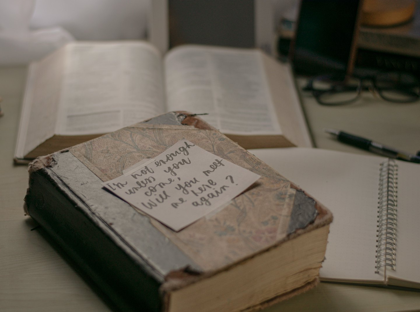 Handwritten note rests on an old book on a desk.