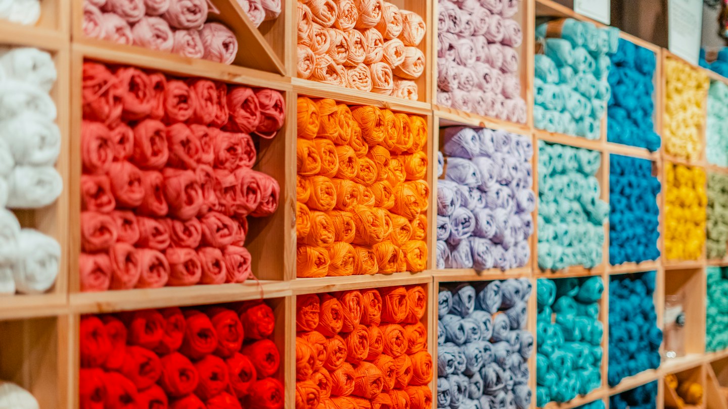 Colorful yarn skeins arranged in wooden cubby shelves.