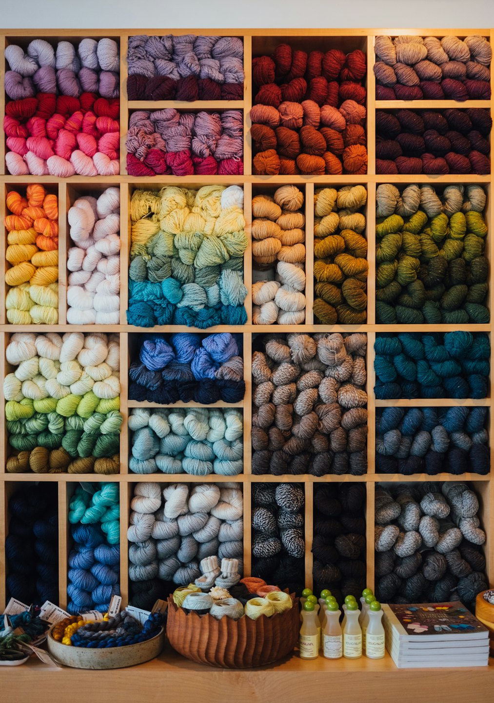 Colorful yarn skeins organized on wooden shelves in a store.